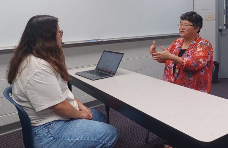 Sophia Geng (St. Vincent College) discusses oral history interview methods with a student member of the University of Central Arkansas team.
